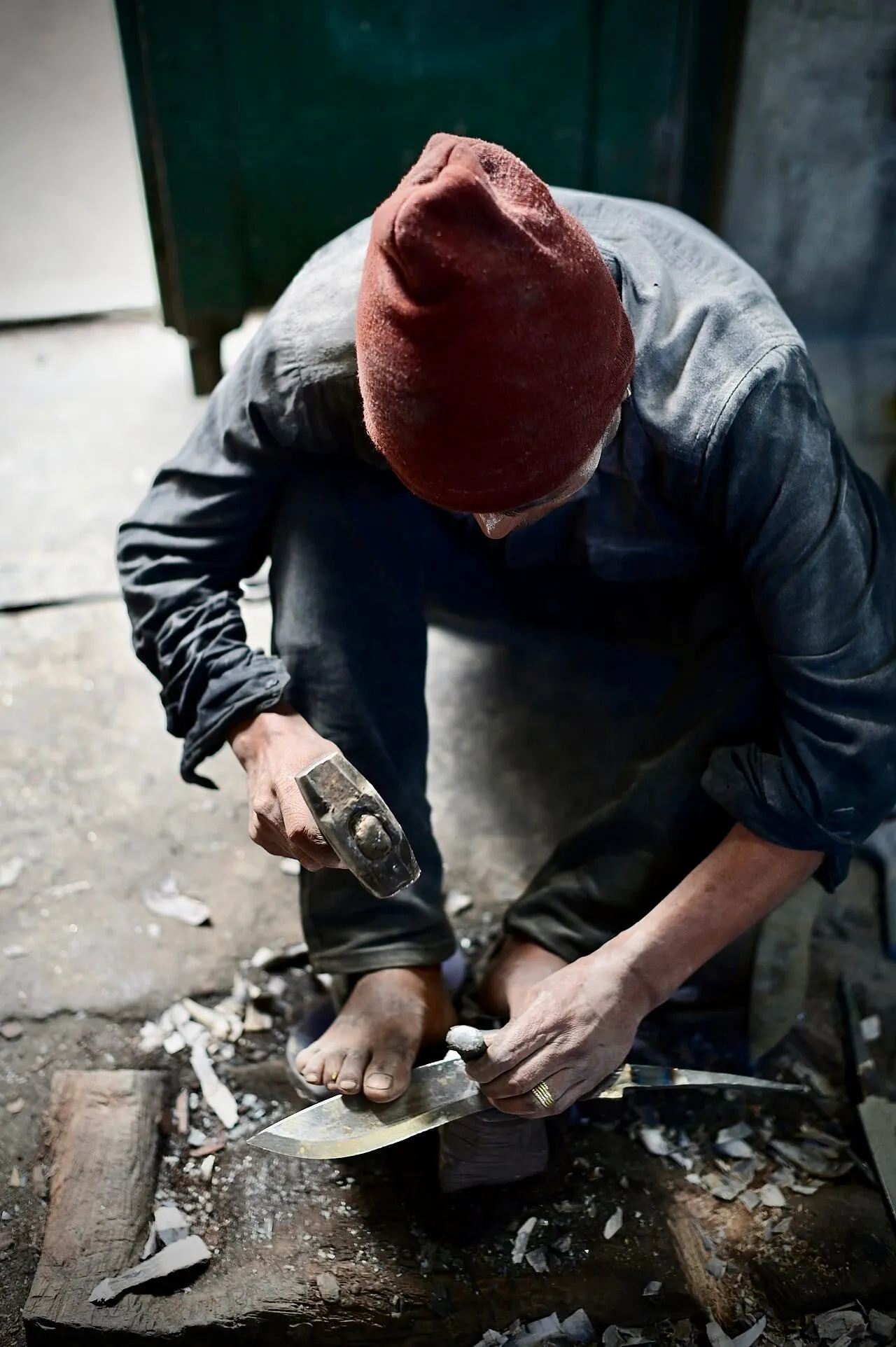 A craftsman hammering the blade of a khukri on an anvil