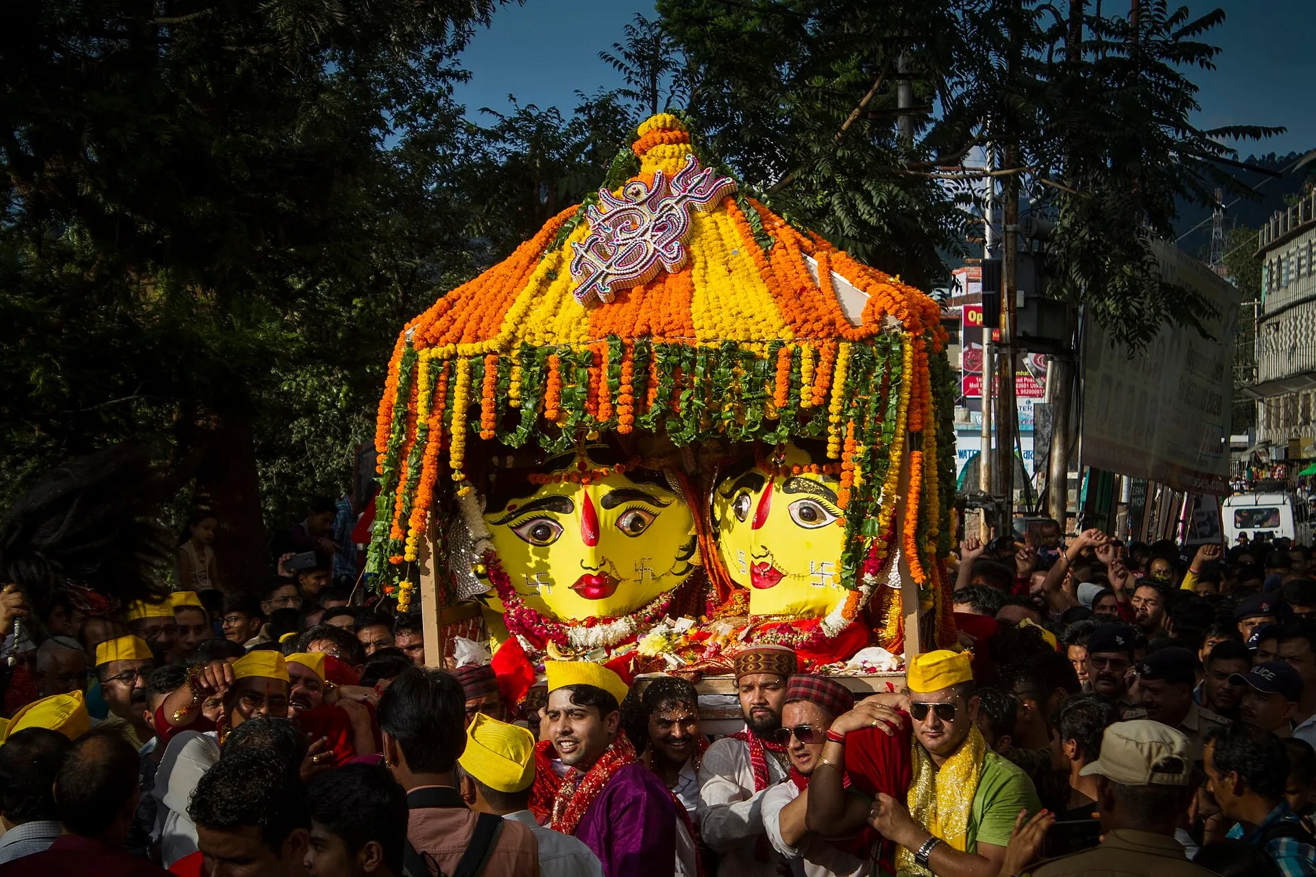 Nanda Devi's dola, crowned with marigolds, carried through a crowd at the Nanda Devi Mela