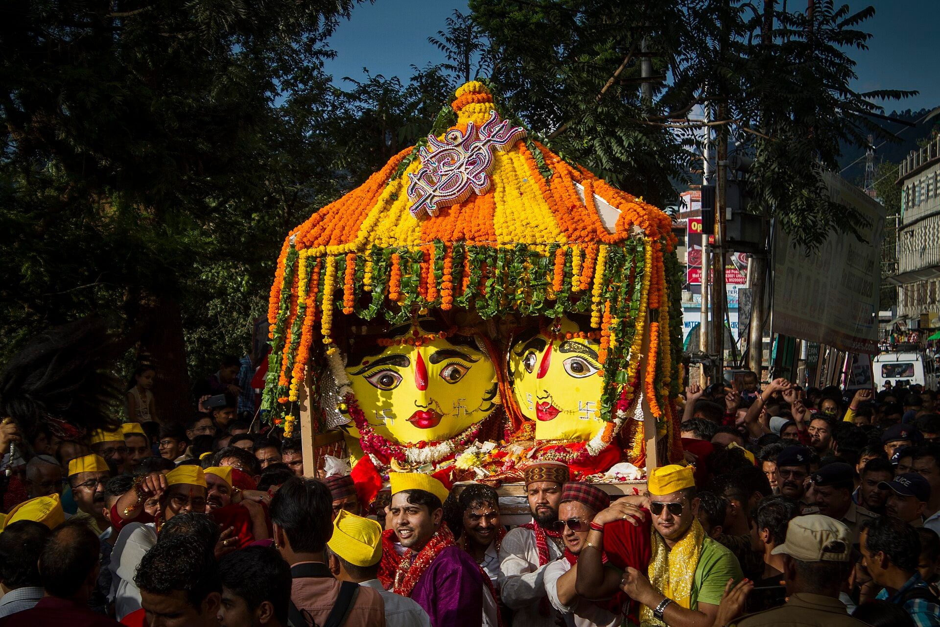 Nanda Devi's dola, crowned with marigolds, carried through a crowd at the Nanda Devi Mela
